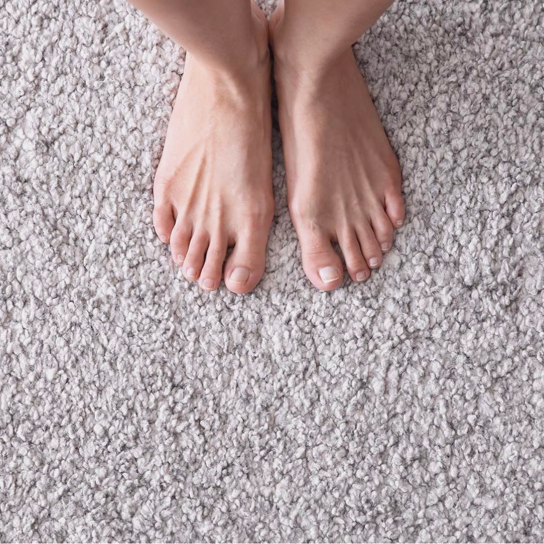 Bàn chân người tập yoga trên thảm trải sàn màu be
