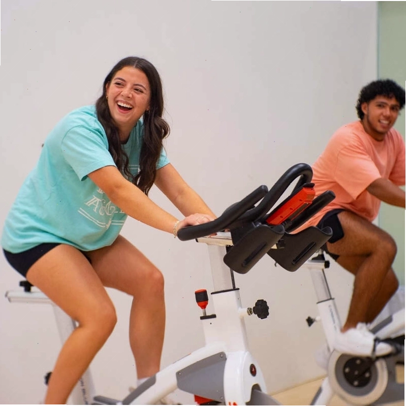 Cặp đôi tập luyện trên xe đạp tập thể dục trong phòng gym sáng sủa