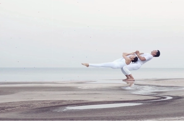 Hai người thực hiện tư thế cùng thở trong Yoga đôi, lưng tựa vào nhau