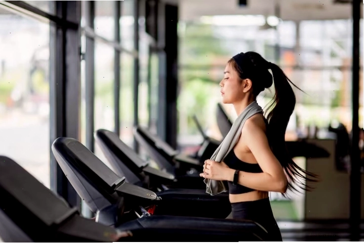 Hình nền người phụ nữ trẻ tập luyện trên máy chạy bộ trong phòng gym