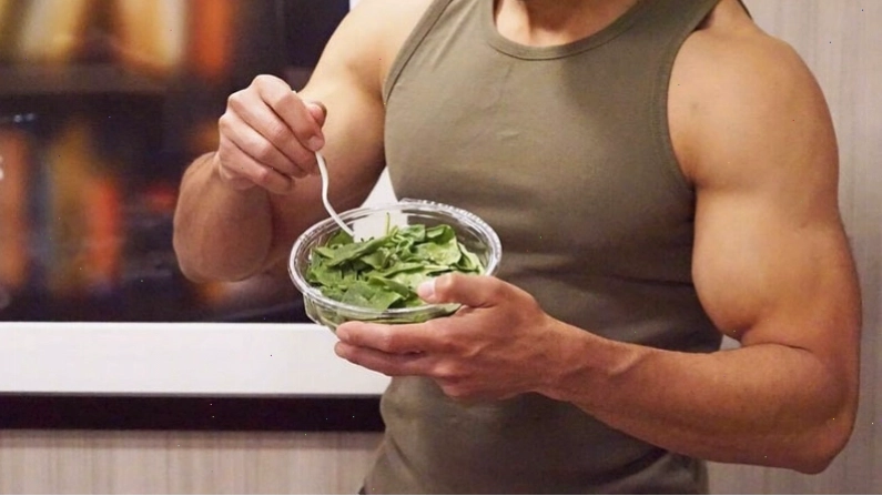 Huấn luyện viên cá nhân hỗ trợ người mới tập gym thực hiện động tác đúng kỹ thuật