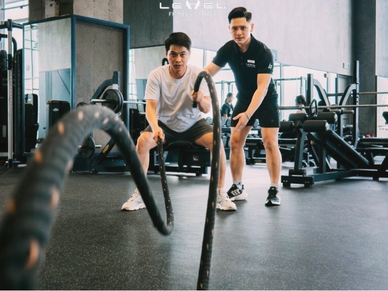 Huấn luyện viên hướng dẫn người mới tập gym