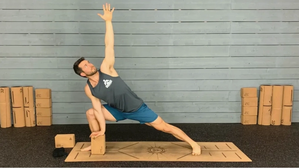 Huấn luyện viên yoga thực hiện tư thế góc nghiêng với tay vươn qua đầu sử dụng khối yoga