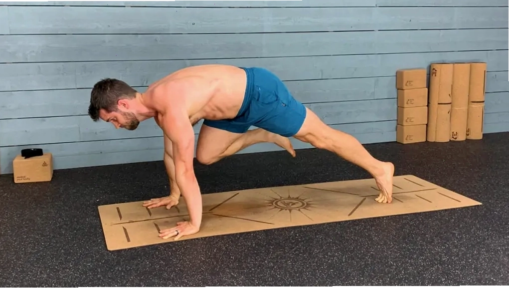 Huấn luyện viên yoga thực hiện tư thế leo núi khuỷu tay chạm gối trên thảm yoga