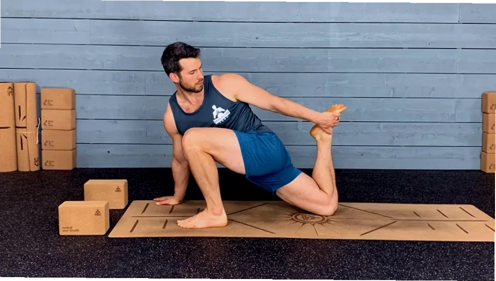 Huấn luyện viên yoga thực hiện và giữ tư thế tấn thấp vươn người về sau trên thảm yoga