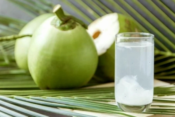 Một ly nước dừa tươi mát lạnh bên cạnh trái dừa nguyên vỏ