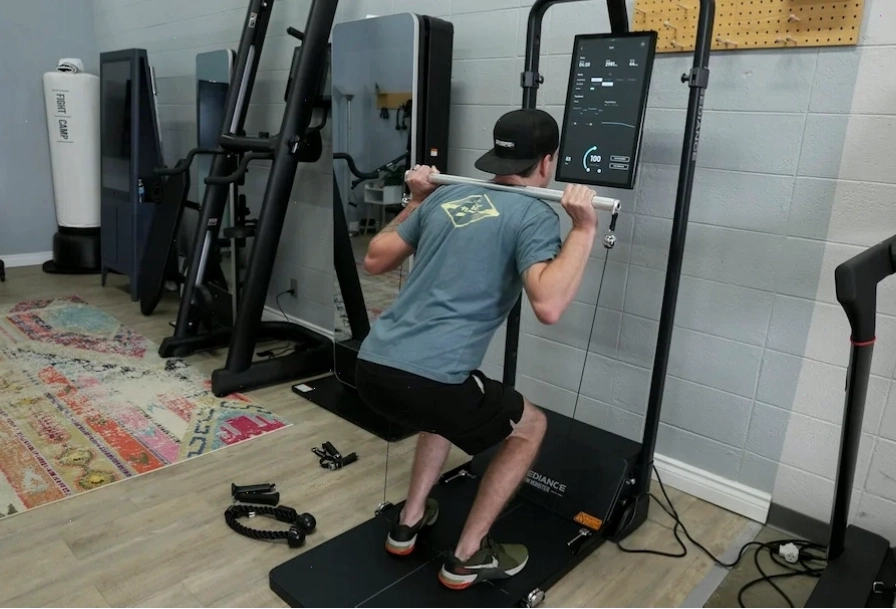 Một người đàn ông mặc đồ thể thao đang thực hiện bài tập back squats bằng Speediance Home Gym