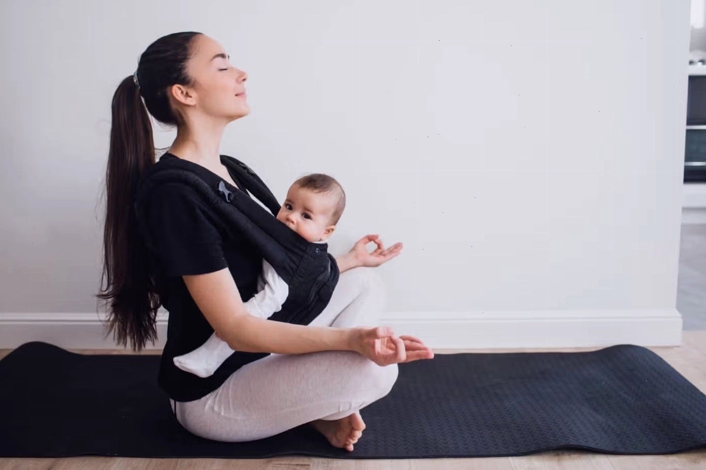 Một người mẹ tập yoga trong khi địu em bé