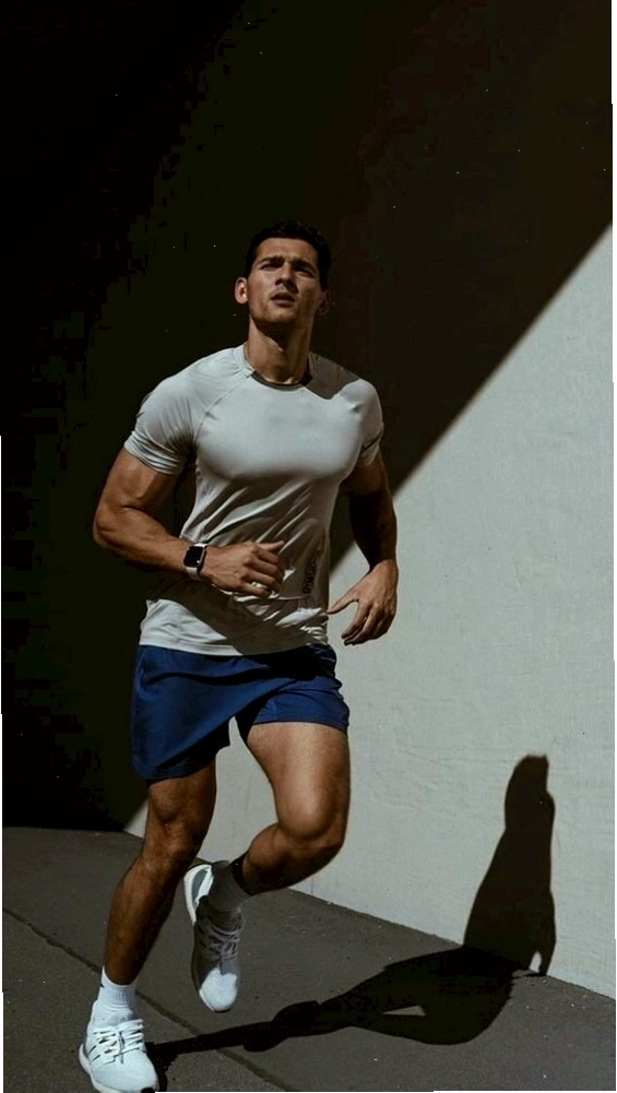Nam gymer chạy bộ dưới ánh nắng, tay ngang hông, đầu ngước lên