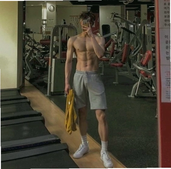 Nam gymer chụp ảnh trước gương, một tay cầm áo, một tay cầm điện thoại, khoe cơ bắp