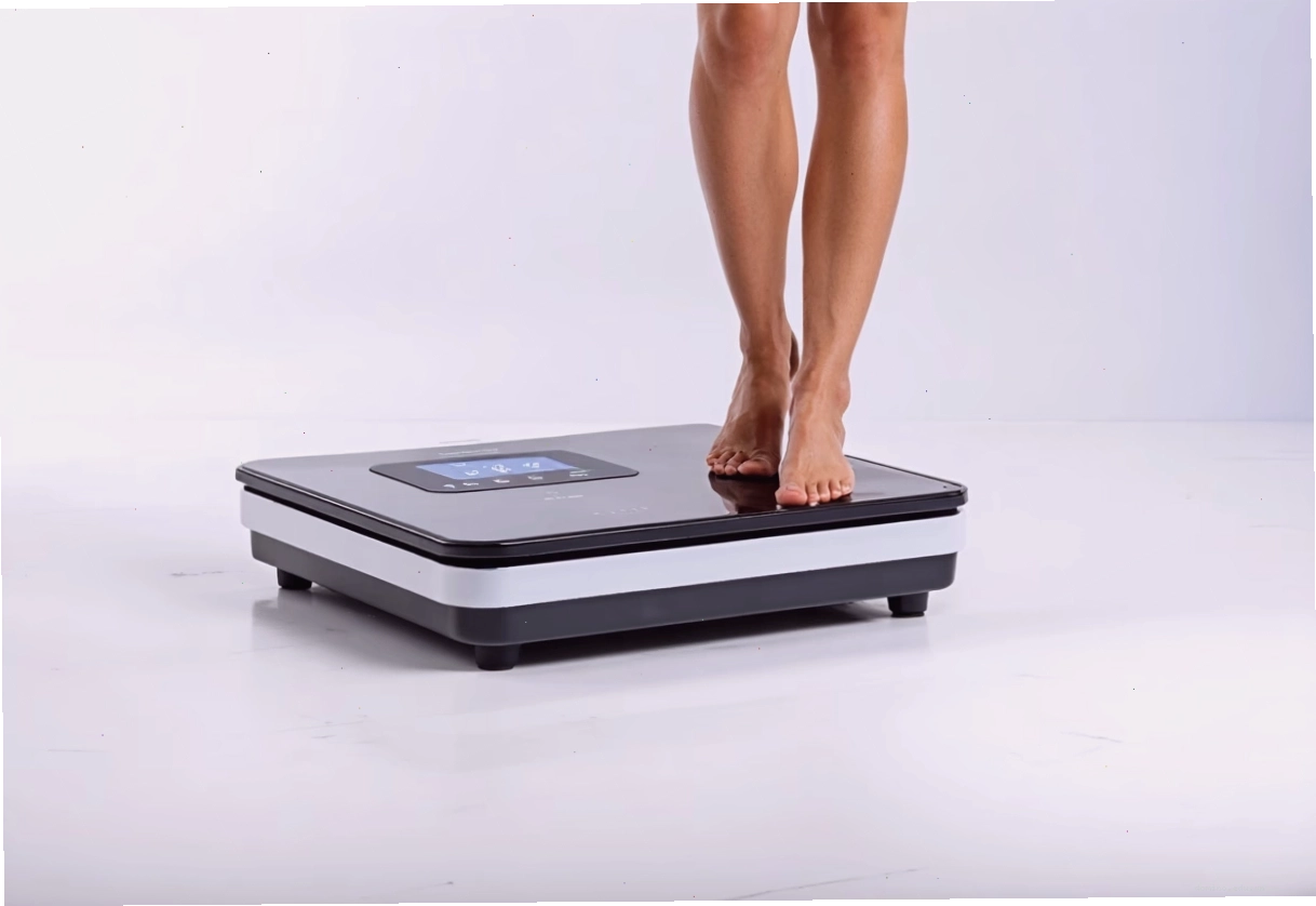 Người đứng trên cân phân tích trở kháng sinh học đo tỷ lệ mỡ cơ thể