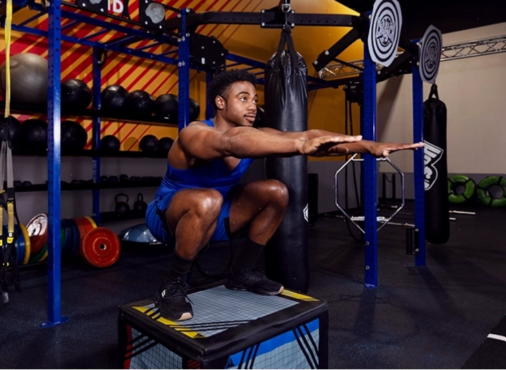 Người tập squat với hộp bật nhảy
