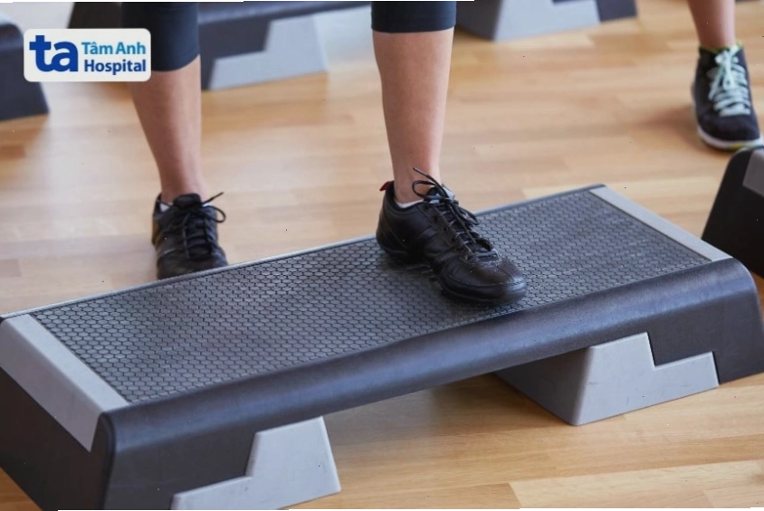 Người tập thực hiện bài tập bước chân lên bục, nhấc cơ thể lên cao.