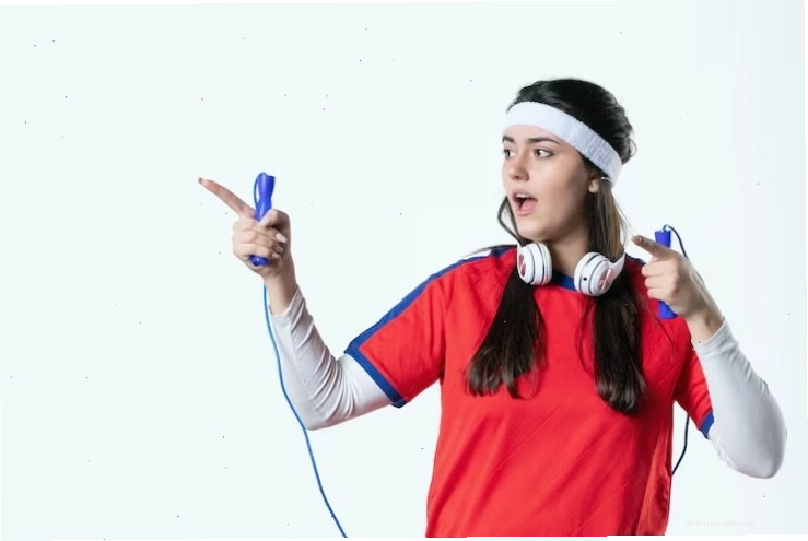 Nhìn trực diện cô gái trẻ mặc đồ thể thao với dây nhảy trên nền tường trắng