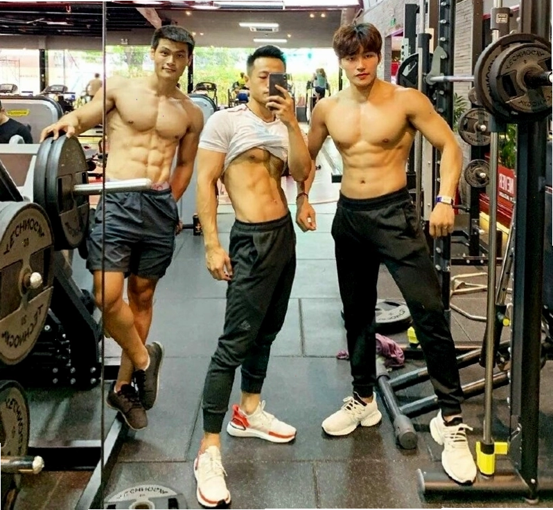 Nhóm 3 nam gymer tạo dáng chụp ảnh, một người vạch áo khoe cơ bụng, người khác gồng tay