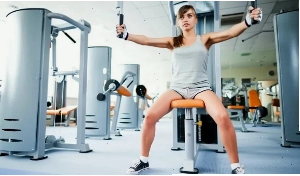 Phụ nữ tập cơ ngực với máy ép ngực trong phòng gym