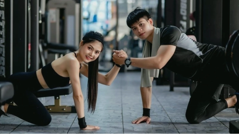 PT Gym hỗ trợ học viên thực hiện bài tập với tạ
