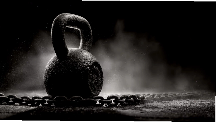 Tạ ấm (kettlebell) nặng trên nền tối có dây xích