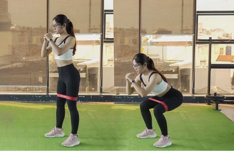 Tập trung giữ thăng bằng khi nhón gót chân phải với dây kháng lực quanh bắp chân
